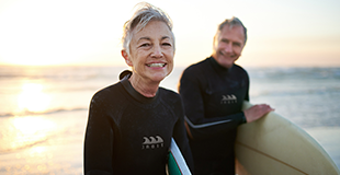 Man and woman holding surf boards by the sea
