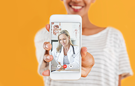 Young woman holding a phone to the screen on which there's a GP on a video call.