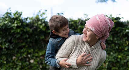 Woman in pink headscarf gets hugged by child