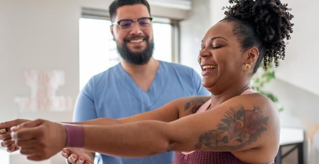 A young woman of colour excercising at the gym with her male friend/personal trainer