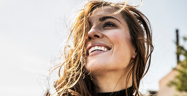 Young woman smiling up at the sky