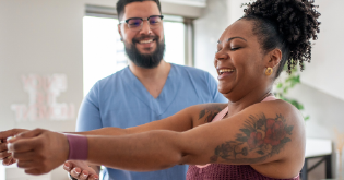 A young woman of colour excercising at the gym with her male friend/personal trainer